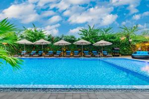 a swimming pool with chairs and umbrellas at Wyndham Garden Hoi An Cua Dai Beach in Hoi An