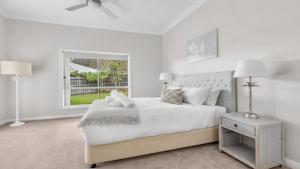 een witte slaapkamer met een groot bed en een raam bij Vintage Lodge in Pokolbin