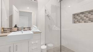 een witte badkamer met een wastafel en een douche bij Vintage Lodge in Pokolbin +10 foto's