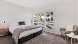 a white bedroom with a bed and a window at Unwined - The Vintage in Pokolbin +6 photos