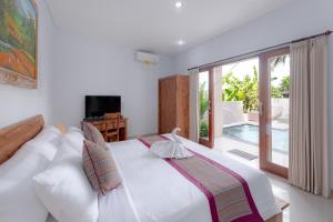 ein Schlafzimmer mit einem großen weißen Bett und einem Balkon in der Unterkunft MAMORU UBUD in Ubud