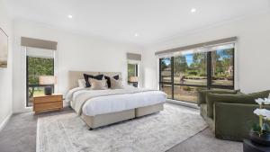 a white bedroom with a bed and a couch at Greenview in Pokolbin