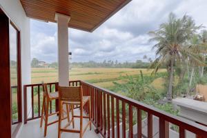 einen Balkon mit 2 Stühlen und Blick auf ein Feld in der Unterkunft MAMORU UBUD in Ubud