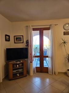 een woonkamer met een televisie en een glazen schuifdeur bij Villa Kety in Prigradica