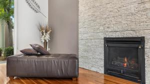 a leather ottoman in a living room with a fireplace at Dashaz Dream - The Vintage in Pokolbin
