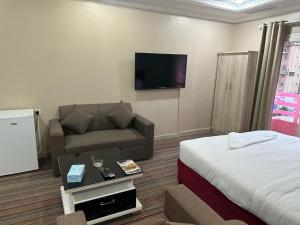 a hotel room with a bed and a couch and a tv at Pyramiza Fahaheel in Kuwait