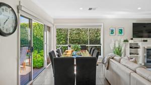 a dining room with a table and chairs and a clock at Cypress Point Lodge - The Vintage in Pokolbin +5 photos