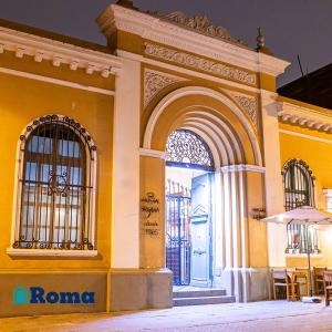 Residencial Roma Bed & Breakfast في ليما: مبنى أصفر مع ممر وطاولات وكراسي