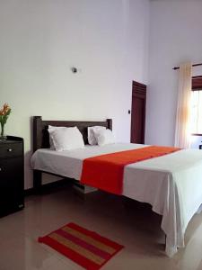 um quarto com uma cama grande e um cobertor vermelho e branco em Villa Serena Galle em Galle
