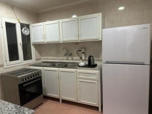 a kitchen with white cabinets and a white refrigerator at Pyramiza Fahaheel in Kuwait