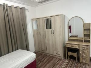 a bedroom with a bed and a vanity and a mirror at Pyramiza Fahaheel in Kuwait