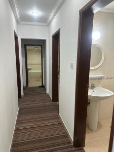 a hallway of a bathroom with a sink and a mirror at Pyramiza Fahaheel in Kuwait