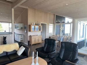 sala de estar con mesa y muebles de cuero negro en Holiday Home With Exceptional Sea View, en Børkop