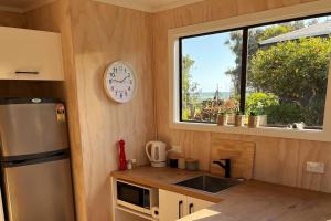 a kitchen with a refrigerator and a clock on the wall at Beachside Gem - Cosy Chalet in Parapara 