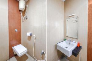 a bathroom with a sink and a toilet and a mirror at FabHotel Prime Mahalaya Residency in Chennai