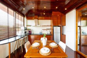 a dining room with a wooden table and a kitchen at Rockstarvillas - Villa Madonna in Bophut 