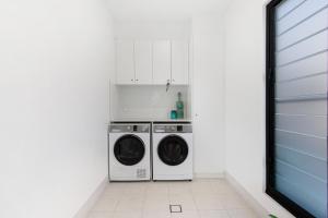 a white laundry room with a washer and dryer at Elvis on Brodie - luxury boutique accommodation in Coffs Harbour