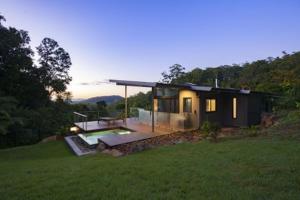 a small house sitting on top of a lush green field at Crystal Creek Rainforest Retreat in Crystal Creek