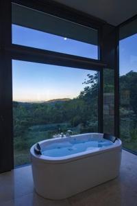 Habitación con bañera grande y ventana grande. en Crystal Creek Rainforest Retreat en Crystal Creek