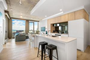 una cocina con armarios blancos y una barra con taburetes en 2BR Apartment in Geelong w/ Spectacular City View en Geelong