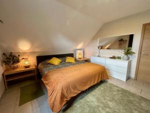 1 dormitorio con cama con almohadas amarillas y espejo en Au Coeur des Collines, Gloriette en Ellezelles