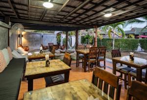 een restaurant met houten tafels en stoelen en een patio bij Phatcharee Resort in Baan Tai