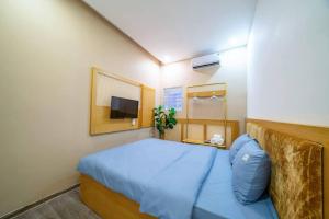 een kleine slaapkamer met een blauw bed en een televisie bij FreePickUp Pool 5 BRs Villa,5 Mins Walk to Beach in Da Nang