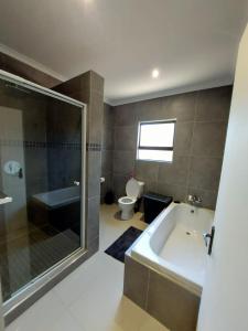 y baño con bañera, ducha y aseo. en Modern Home Accommodation en Zeerust