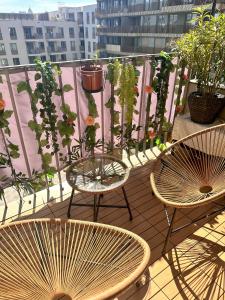 2 Stühle und Tische auf einem Balkon mit Pflanzen in der Unterkunft The Laendyard in Wien