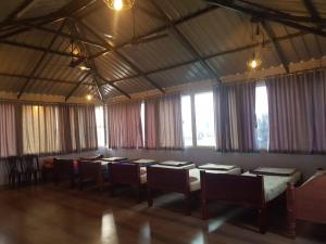 una grande stanza con tavoli, sedie e finestre di Fourseason frankcottage a Chikmagalūr