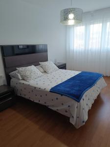 een slaapkamer met een bed met een blauw en wit dekbed bij Piso familiar próximo a Santiago de Compostela y La Coruña in Ordes