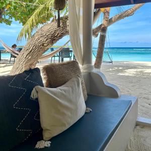 eine Couch am Strand mit Hängematte in der Unterkunft Canopus Retreat Thulusdhoo in Thulusdhoo