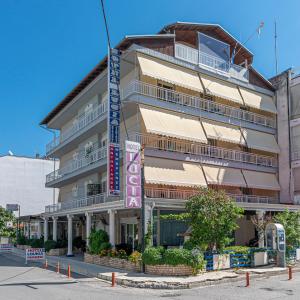 um edifício alto com um sinal em frente em Lucia Hotel Paralia em Paralia Katerinis