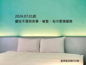 una señal sobre una cama con almohadas blancas en Taimali Hotel, en Taimali