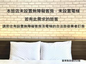 eine Ziegelwand mit chinesischem Schreiben über einem Bett in der Unterkunft Taimali Hotel in Taimali