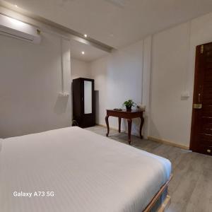 a bedroom with a white bed and a table at Arambol Sweet Lake Resort in Arambol