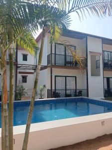 a villa with a swimming pool and palm trees at Arambol Sweet Lake Resort in Arambol