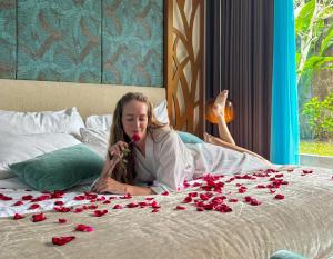 a woman laying on a bed with roses on it at The Leaf Jimbaran Luxury Villas in Jimbaran