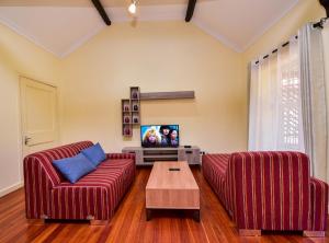 een woonkamer met twee rode banken en een tv bij A PLACE OF TRANQUILITY, Muthaiga in Nairobi