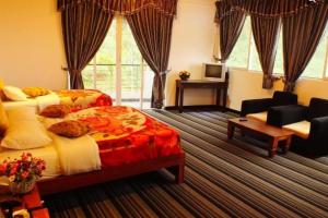a bedroom with two beds and a couch and a desk at New Ashley Resorts (PVT) LTD in Nuwara Eliya
