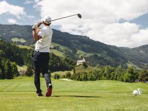 a man swinging a golf club on a golf course at Chalet in Zillertal near Ski Slopes in Aschau