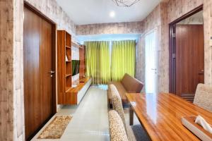 une salle à manger avec une table et des chaises en bois dans l'établissement RedLiving Apartemen Grand Kamala Lagoon by Ownr Room, à Pekayon Satu