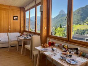 a dining room with two tables and large windows at B&B Lavi Ortisei val Gardena in Ortisei