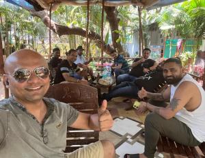 a group of men sitting around a table giving a thumbs up at Nature of Arambol in Arambol
