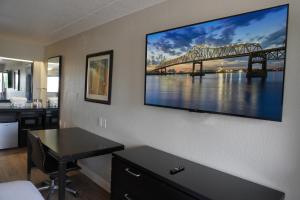 um quarto de hotel com uma grande televisão na parede em Boardwalk Suites Baton Rouge em Baton Rouge