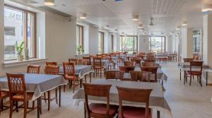 uma sala de jantar com mesas, cadeiras e janelas em Summer Hotel Tott em Savonlinna