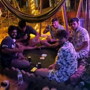a group of men sitting on the floor playing poker at Nature of Arambol in Arambol