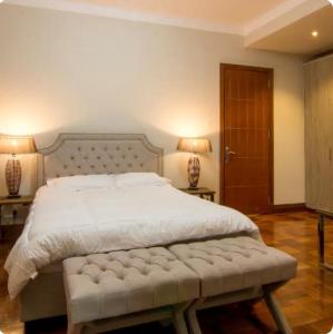 1 dormitorio con 1 cama grande con colcha blanca en Palm House en Nairobi