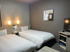福島市にあるHotel Route Inn Fukushima Nishi Interのベッド2台とテレビが備わるホテルルームです。