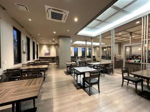 Hotel Route Inn Fukushima Nishi Inter في فوكوشيما: مطعم بطاولات وكراسي خشبية ونوافذ